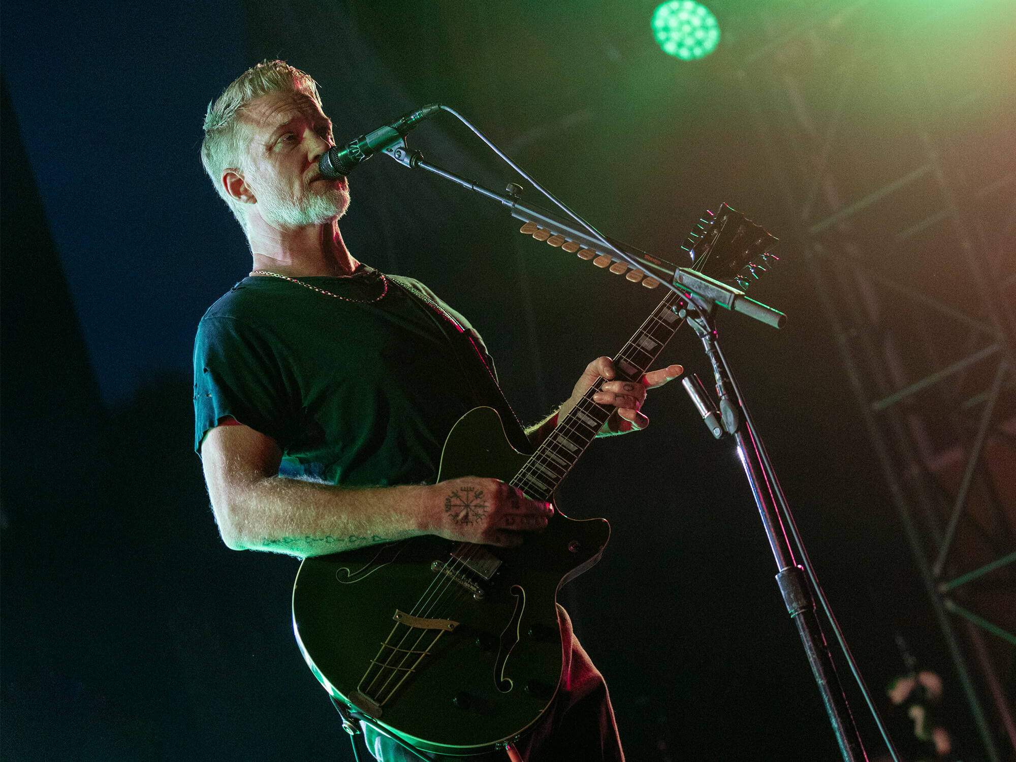Queens of the Stone Age frontman performing with guitar at a live show